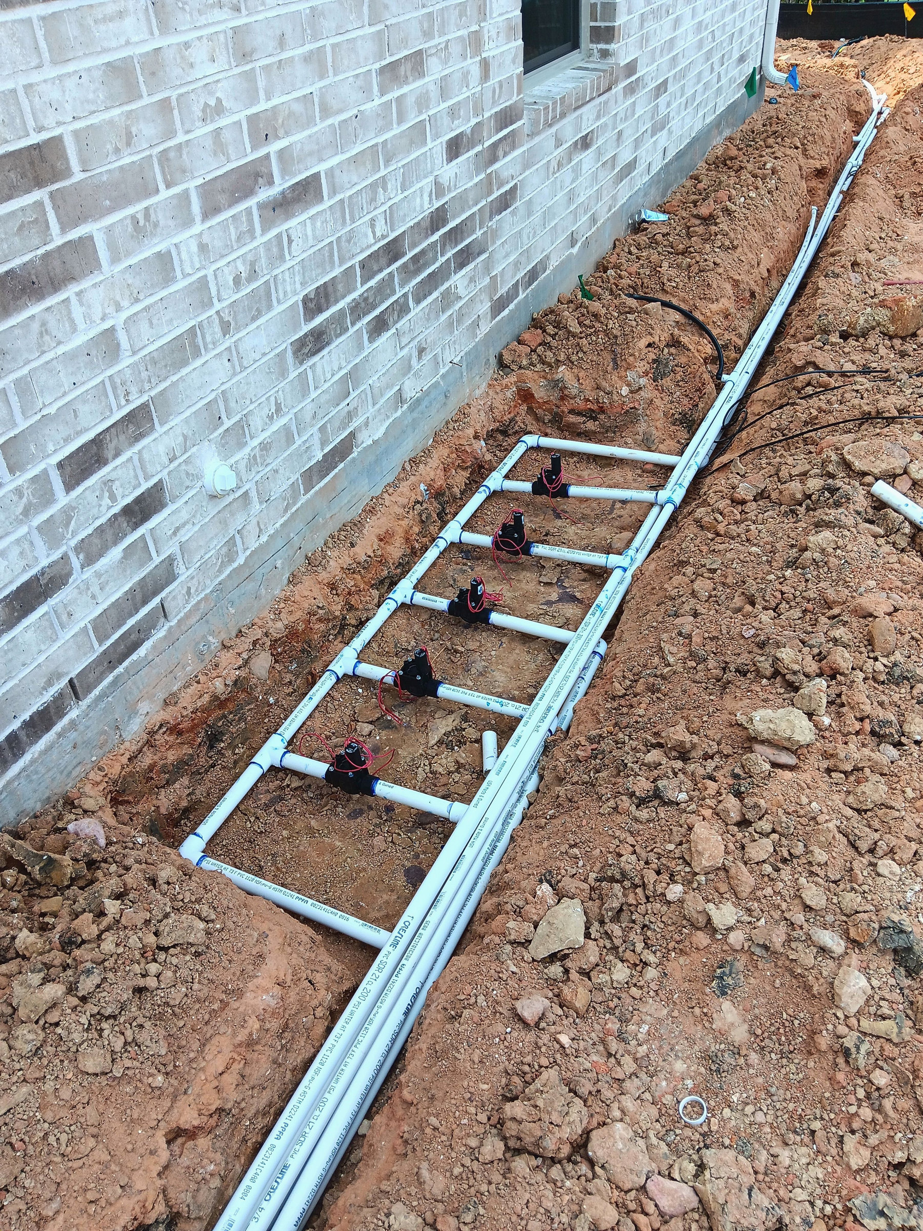 Irrigation PVC installation beside brick wall